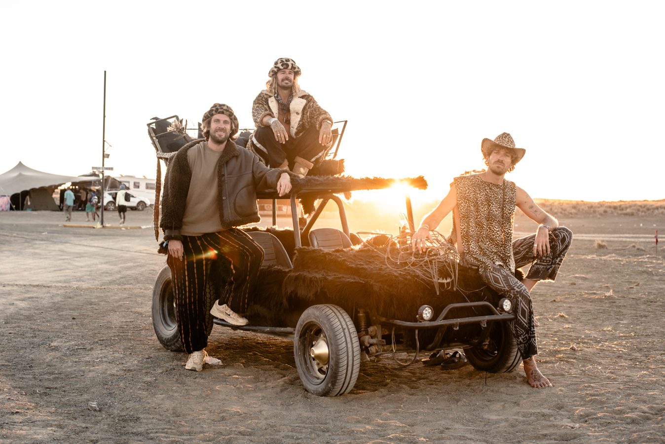 A crew on and around a dune buggy at sunset