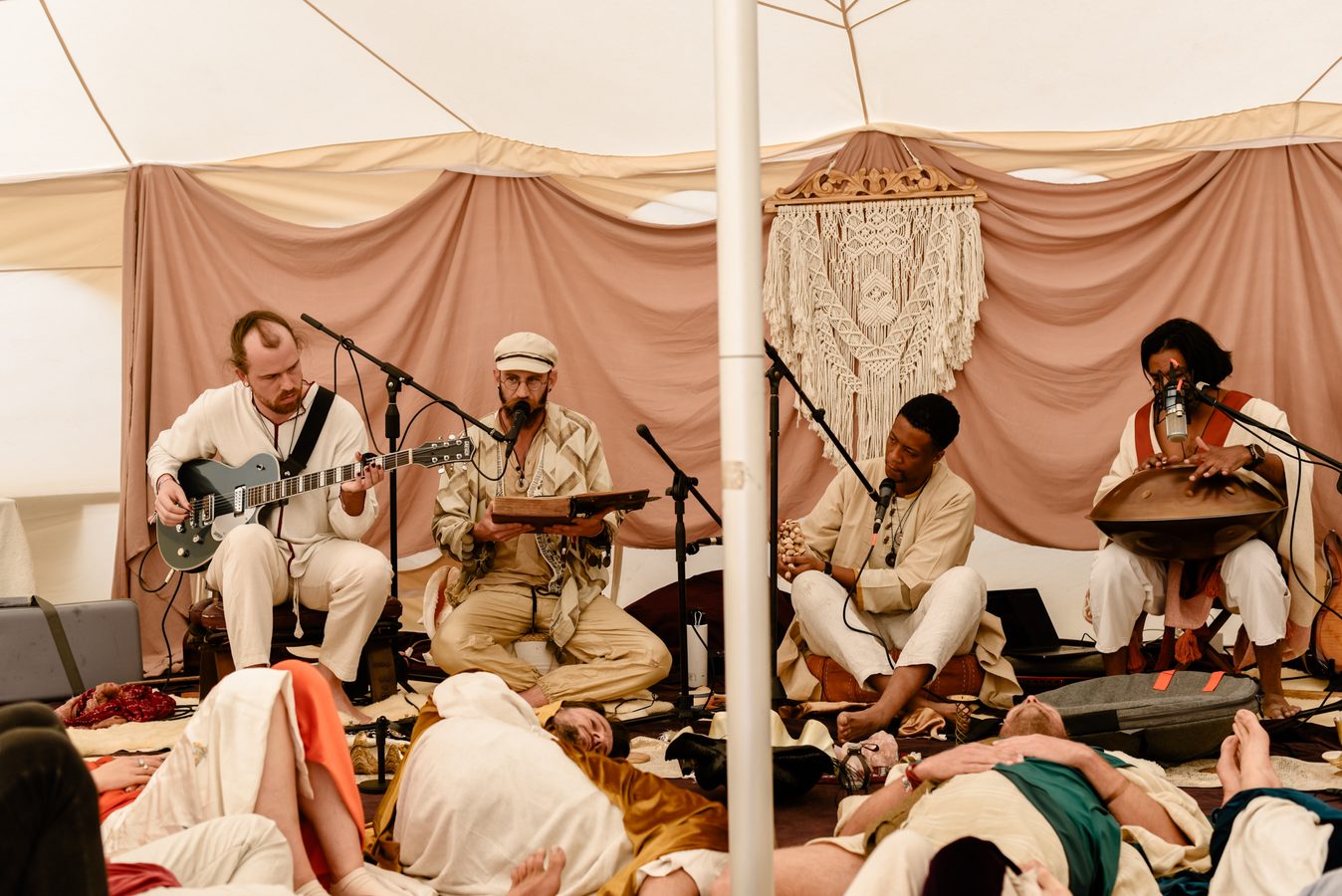Musicians playing inside the tent while people lie and listen