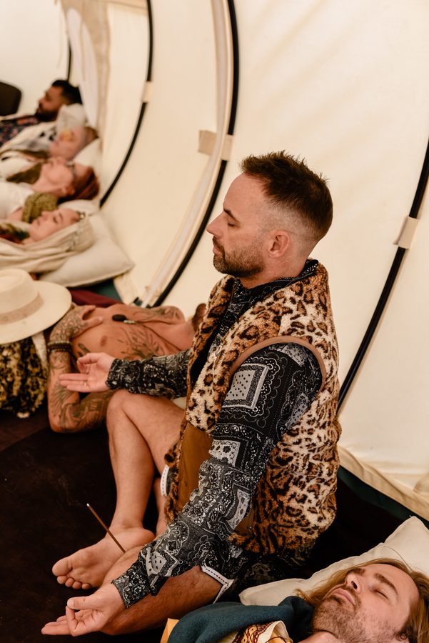 A camp mate sitting still in meditation inside a bell tent