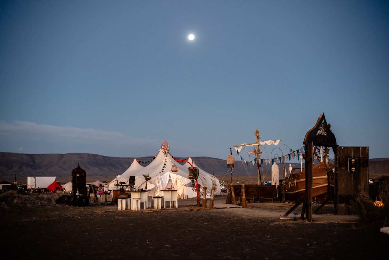 The whole camp at dusk under a rising moon
