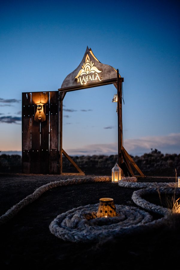 The MAHALA gateway at night, a lantern hanging in it and a spiral of rope before it