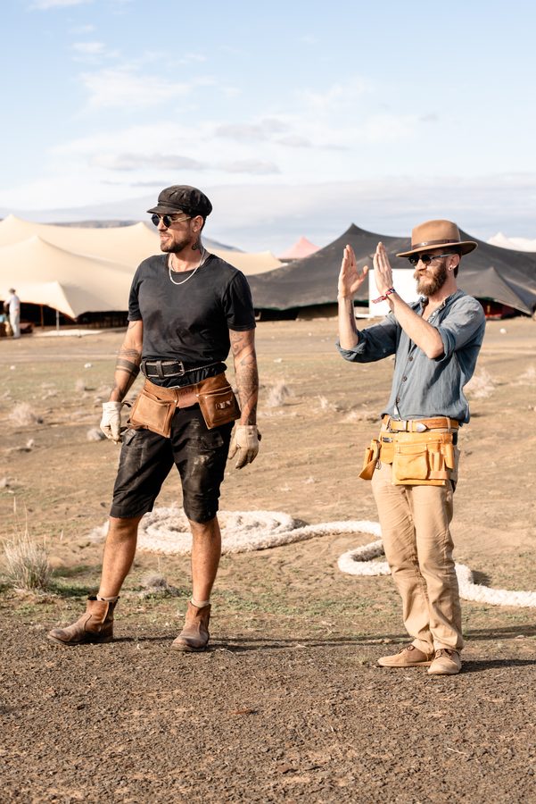 Two builders with tool belts sharing a laugh on the build site
