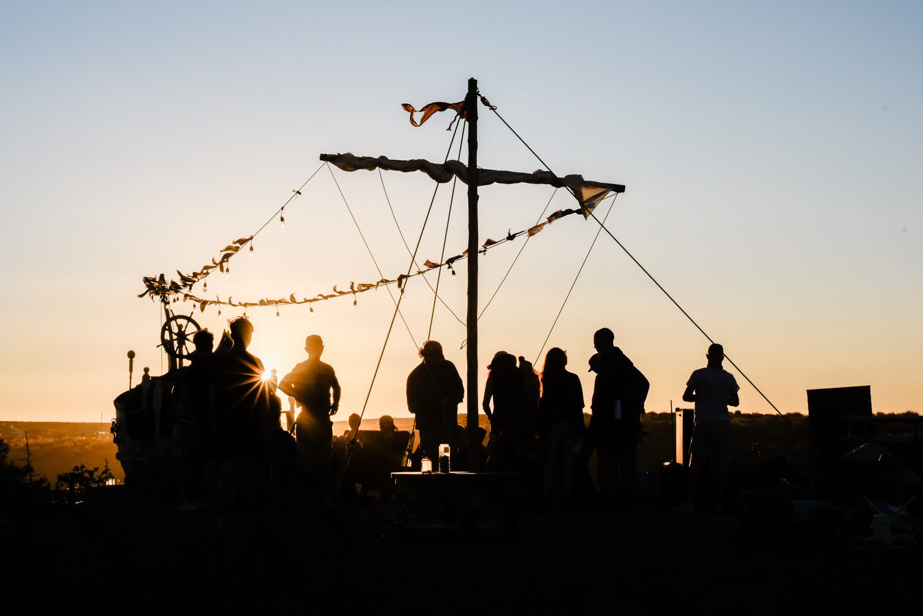 Camp mates in silhouette on the boat deck against the sunset