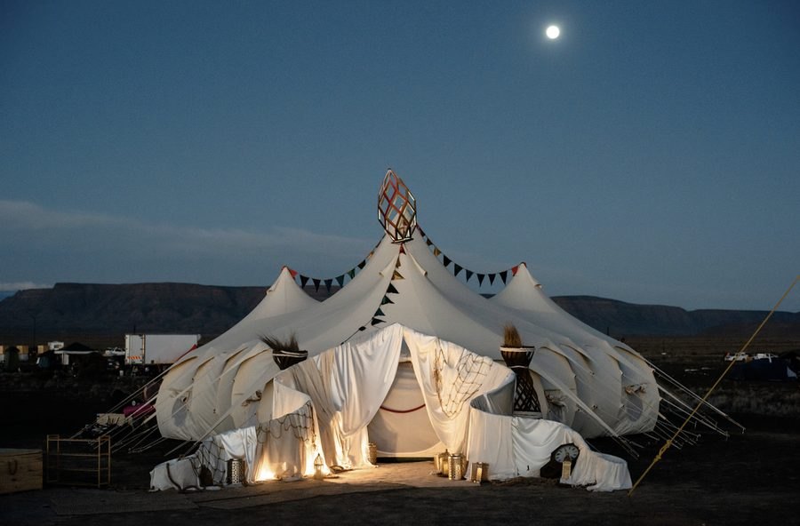 Mahala's big tent lit at dusk under the moon